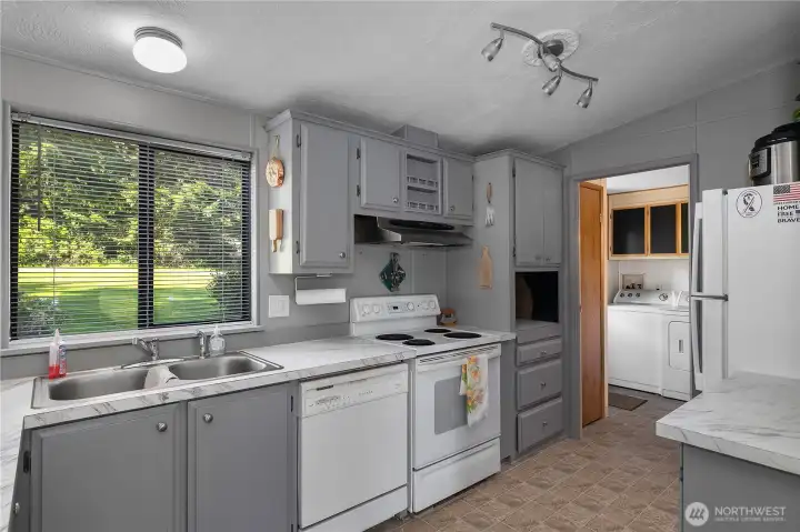 Enjoy efficient kitchen workspace with generous counter area, gray cabinetry, and laundry nearby.