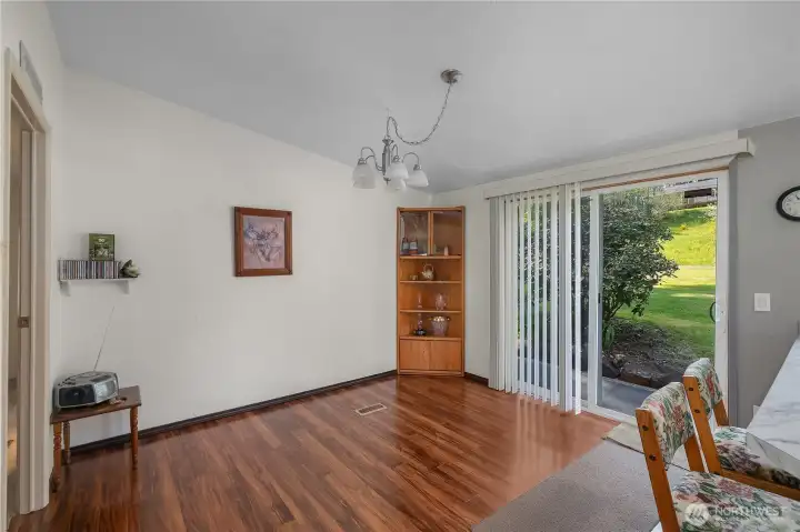 Dining nook offers wood-style flooring, a sliding glass door, and a pleasant view to the yard.