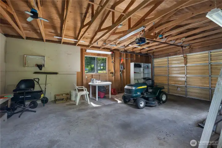 Garage interior offers practical storage, work space, and overhead door access.
