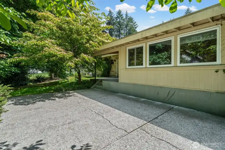 A generous concrete patio wraps the side of this home, shaded by a mature flowering tree and surrounded by lush Pacific Northwest greenery. Plenty of room for entertaining, gardening, or simply enjoying the outdoors.