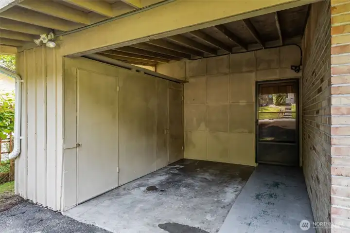 The covered carport at this Eastgate Bellevue rambler includes built-in storage rooms and a direct entry door to the backyard — practical, protected parking with extra storage.