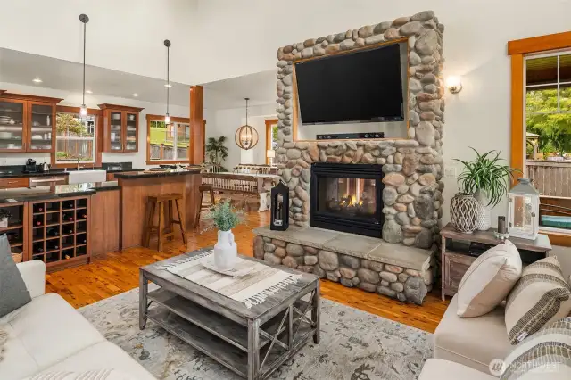 Great room with raised hearth river rock fireplace. Double sided to enjoy from the interior and also on the covered deck!