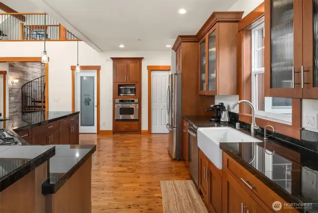 Large chef kitchen with cooking island, eating bar, farmhouse sink, stainless appliances and walk-in pantry.