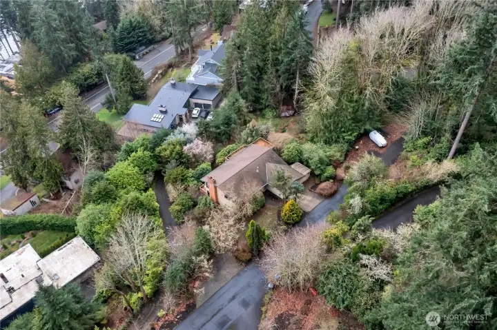 Drone view of home with brown roof on private road.
