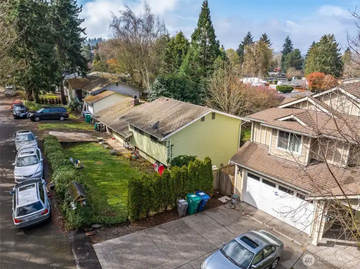 Elevated view capturing the home’s position along a quiet residential street with nearby greenery.