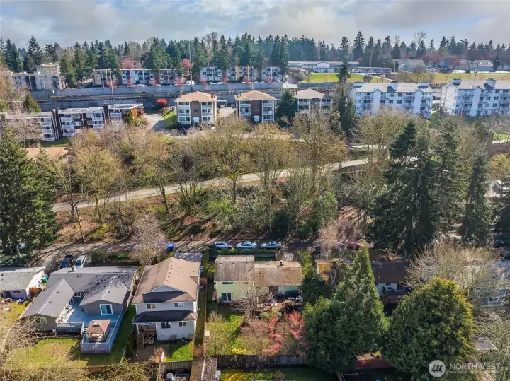 Expanded aerial view showing nearby housing, tree-lined streets, and overall neighborhood density.