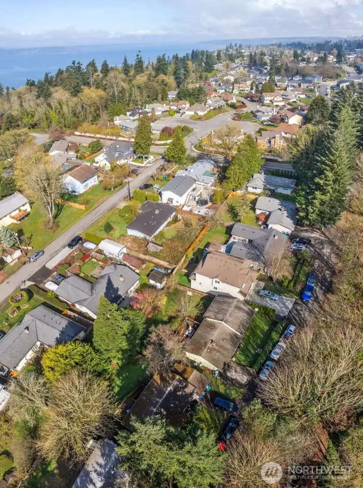 Wide aerial perspective highlighting surrounding homes, street layout, and proximity to nearby residential areas.