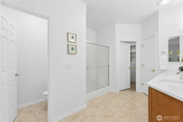 Spacious primary bathroom has dual sink vanity, large step-in shower, walk in closet, linen closet, and separate water closet.