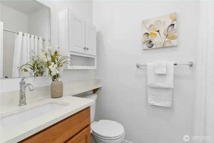 Full hall bathroom updated in 2025 with new quartz countertop & backsplash, new mirror and light fixture, and new faucet. Storage cabinet installed in 2024.