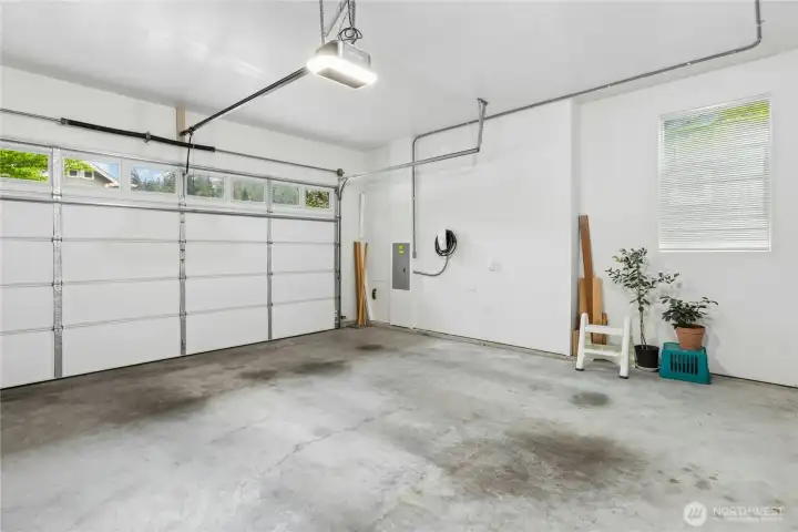 Two car garage has new insulated garage door with windows for natural light, along with smart motor, myQ, and keypad opener (all installed in 2025). Built in shelving on side wall (not pictured) provides extra storage space.