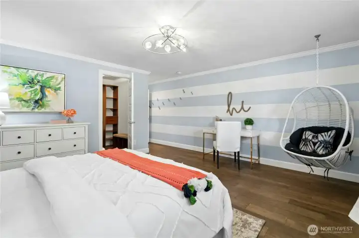 This spacious main floor bedroom features a playful hanging chair, custom light fixture, and a large walk-in closet with built-in organization.