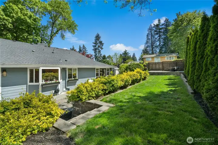 The upper terraced level adds another layer of usable outdoor space, with a broad lawn, mature privacy screening, and elevated gathering areas woven into the landscape design.