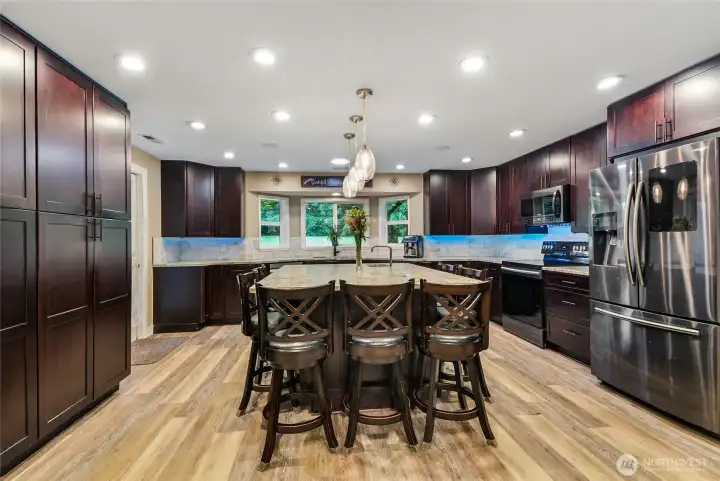 Stunning remodeled kitchen with large island, dark cabinetry, and gorgeous vinyl plank floors.