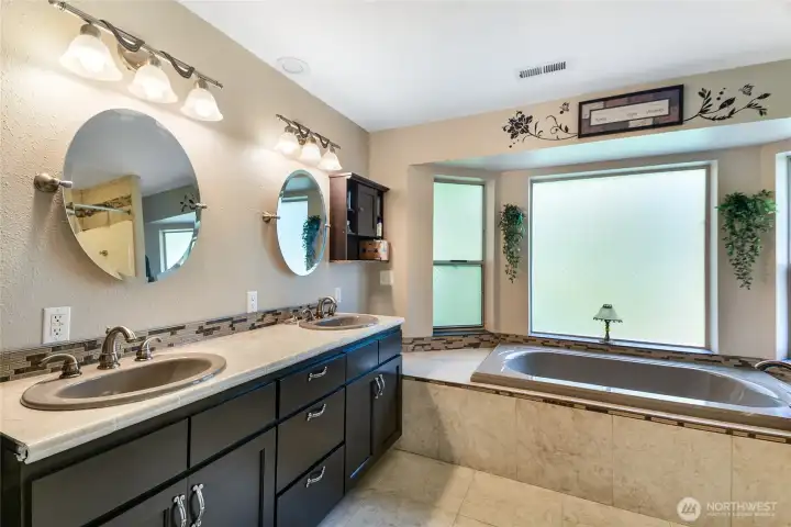 Luxurious primary bath with dual vanity, jetted tub, and beautiful finishes