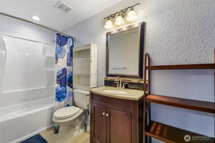 Full bath with tub/shower combo and warm wood vanity