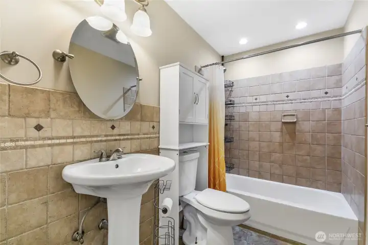 Full bath with pedestal sink and tiled walls