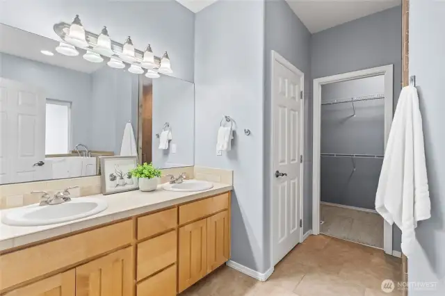 There is a generous amount of storage space in the primary bathroom. Note the double sinks, large mirror, and access to the walk-in-closet.