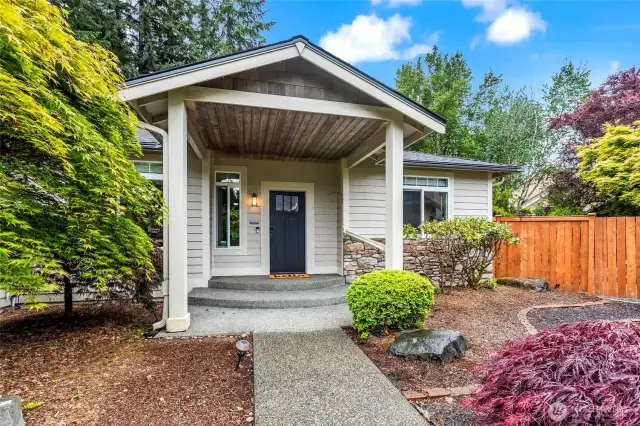 The covered front patio greets visitors with a modern front door in a sophisticated color. The stone façade and meticulous landscaping add to the features of this home.