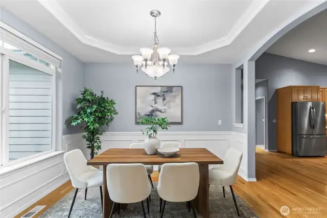 The spacious dining room has a coffered ceiling with crown molding and wainscotting with an added chair rail.