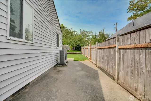The north side of the backyard is paved and ideal to hold a storage shed for your garden tools. Note the almost-new heat pump for comfortable inside temps!