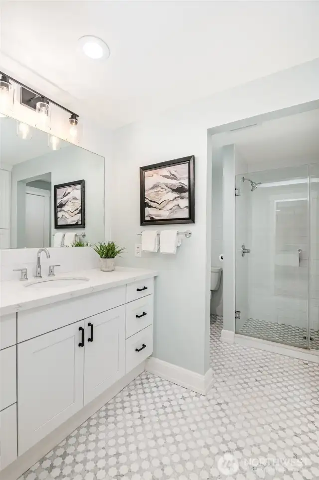Beautifully updated primary bathroom with extra large shower, tile flooring and storage.