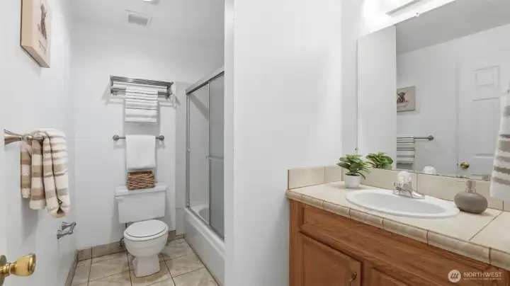 Convenient upper-level bath with ample vanity storage and full shower enclosure.