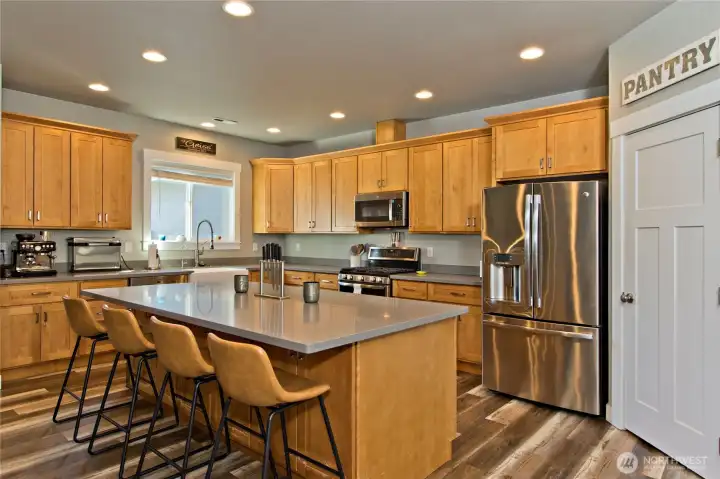 Kitchen with large center island, stainless steel appliances, and pantry.