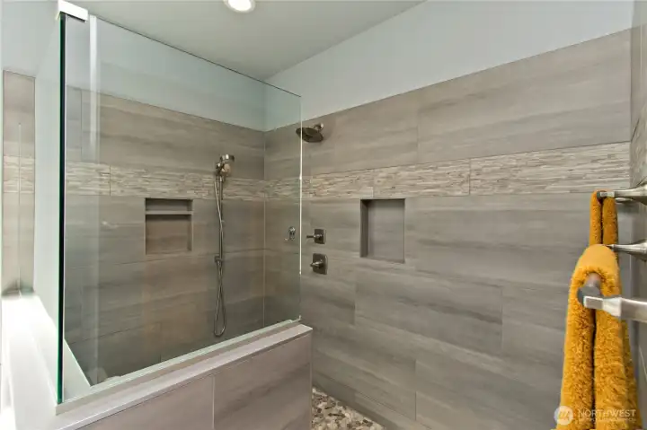 Spa-like primary shower with custom tile and built-in niches.