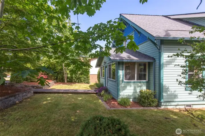 A side yard view captures the home's vibrant blue siding alongside a neat lawn area and a raised garden bed.