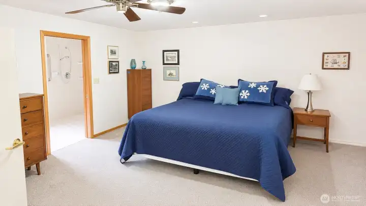 Primary bedroom with ceiling fan, extra closet space and pocket door leading to oversized bathroom.