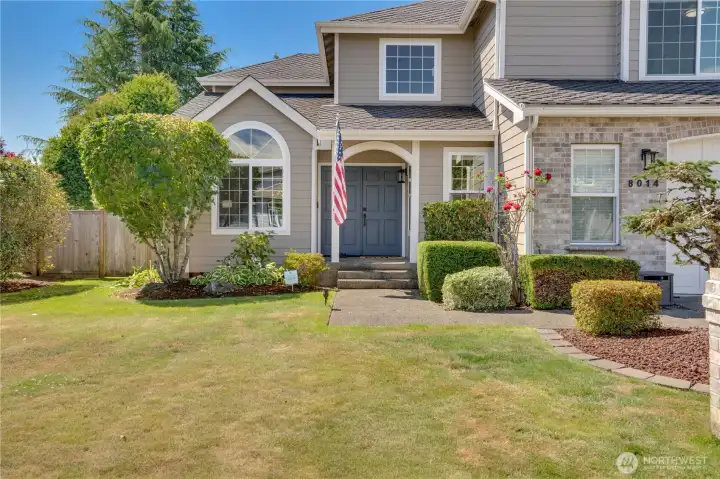 A manicured approach leads to the covered front porch, where 2022 exterior paint and new front light fixtures installed in 2026 create a polished first impression.