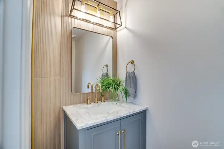 The refreshed powder room features contemporary finishes, updated fixtures, and distinctive fluted wood detailing that adds warmth and character for guests.