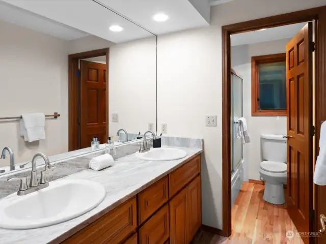 Top floor guest bathroom with new vanity, countertop, sinks, floors, toilet, and glass shower door.
