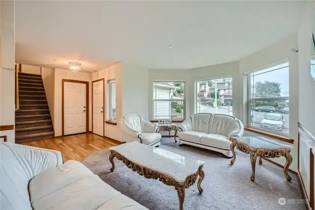 This elegantly appointed living room offers an inviting and serene atmosphere, perfect for both relaxation and entertaining. Featuring large bay windows, the room is bathed in natural light, creating an airy and open feel.