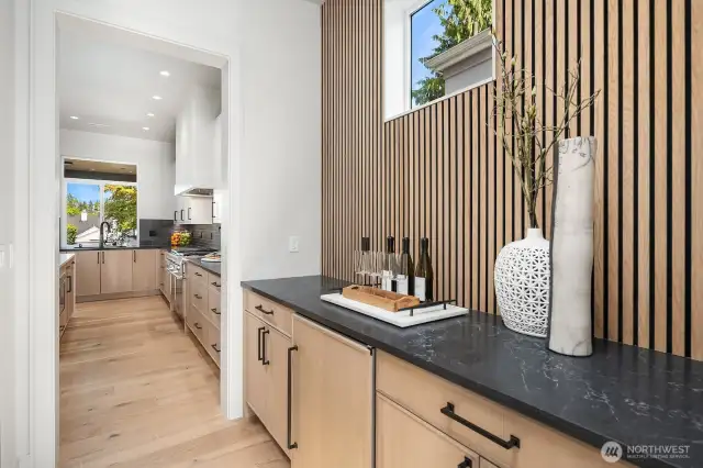 The Butlers Pantry with clear story window, custom wall design, Belmont cabinets and beverage refrigerator. The door to the right is the full walk in pantry with custom shelving.