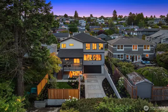 A view of the back of the home at dusk with the long driveway that could easily hold many cars.