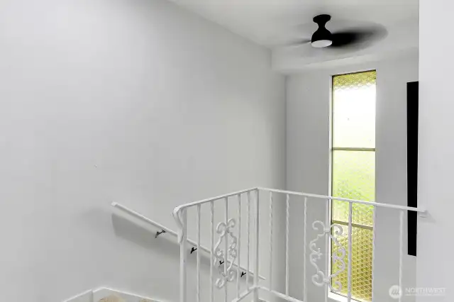 Bright and airy stairwell with vintage inspired railing and unique privacy glass window detail.