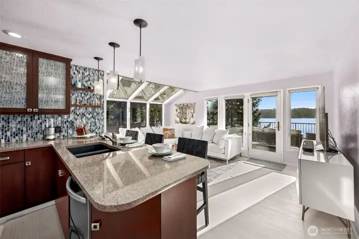 The remodeled kitchen blends effortlessly into the styling of the home with rich cabinet finishes, granite countertops and a  tile backsplash all evoking the natural tones of the water and bordering forest.