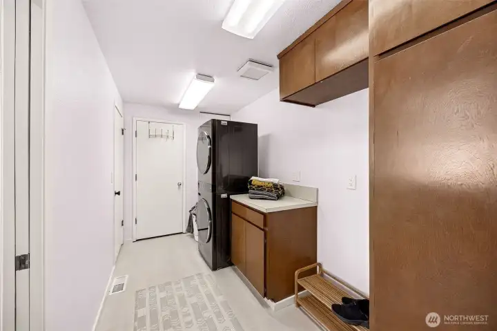 The large utility room with extra storage and pantry closet leads to the main floor 3/4 bath seen in the background and the exterior door to the breezeway and garage for easy loading and unloading.