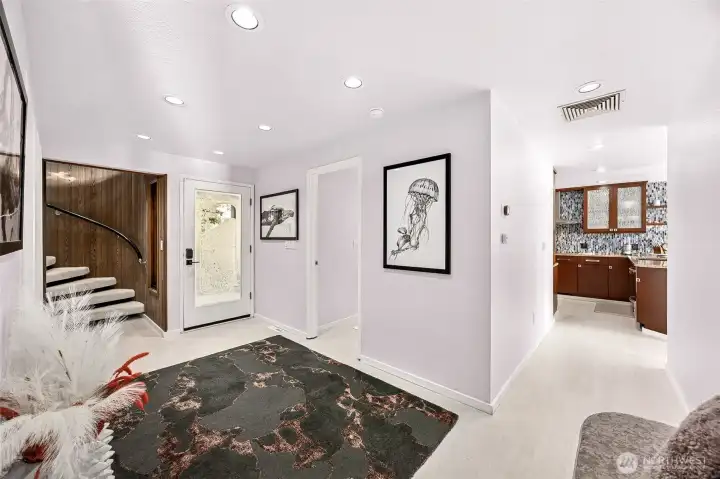 The front entry hall serves as an axis point to all areas of the home.  The classic spiral stair way highlights the unique NW styling of the home. The main floor bedroom sits across from the bath.  Photo from living area.