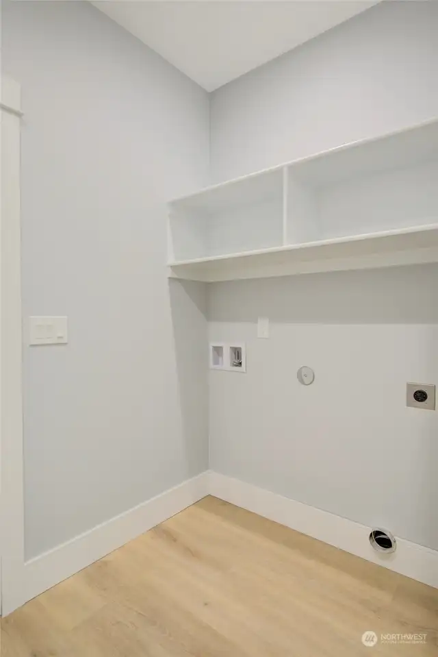 The laundry room with shelving has access to the double car finished garage.