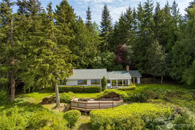 Charming single-level home nestled against a lush forest backdrop with panoramic water views and a view deck for ultimate relaxation.