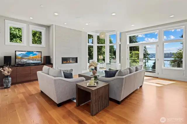 Sunlit living room with expansive Marvin windows that capture the shimmering water views