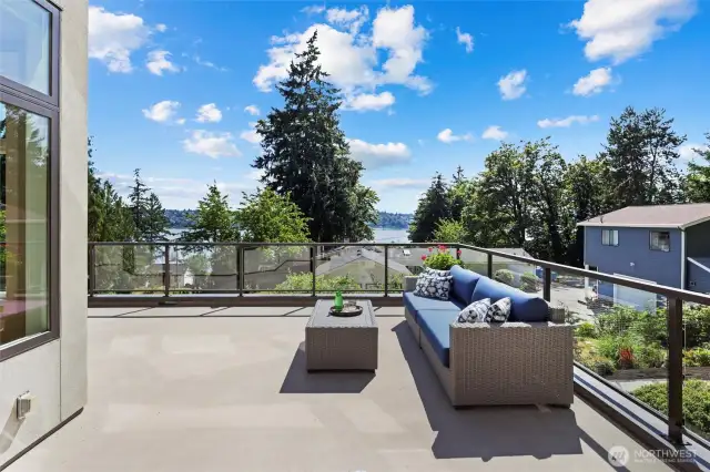 The main floor deck spans the entire width of the main floor with entrances from the Living Room, Nook and Dining Room. Stepping onto the deck from the Dining Room, note the metal frame railing and crystal clear glass panels that show the entire view from any location on the deck.