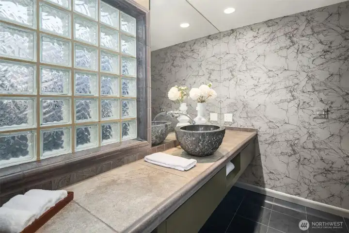 A large glass-block wall welcomes natural light into the main-floor 3/4 bath (the shower is out of frame on the right.)
