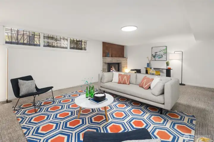 The lower level family room has nice ceiling height and loads of space, and features a gas fireplace with original midcentury stone surround and cool wood detailing above the mantle.