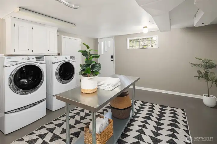The lower level laundry is bright and spacious, with cabinetry and a utility sink (just out of frame on the left) and ample space for a large folding table.  The door with the 3 windows leads to the driveway and stairs up to the front patio.  The door on the left leads to the attached  2-car garage.  To the right is the hallway to family room and non-conforming bedroom.  Just behind us out of frame is a 3/4 bath.