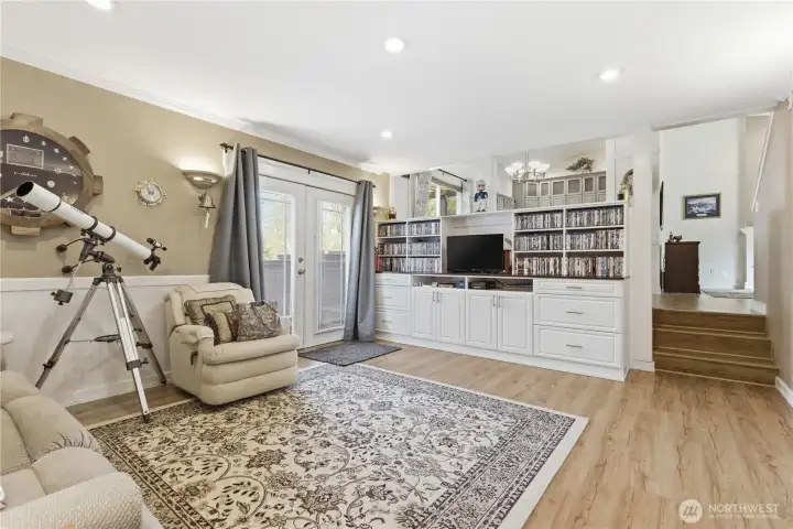 Built-in cabinetry and wainscoting add warmth to the family room, with French doors leading to the garden