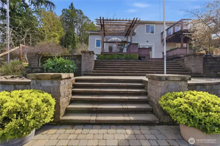 Extensive stonework surrounds a lush backyard filled with fruit trees, roses, and vibrant plantings—a true gardener’s dream