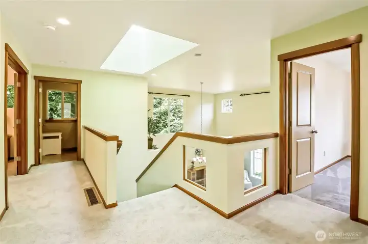 Sky-lit second floor landing with windows overlooking the living & dining areas.